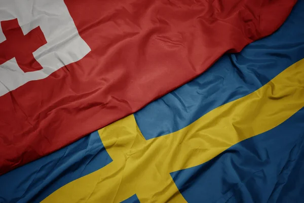 Waving colorful flag of sweden and national flag of Tonga . — Stock Photo, Image