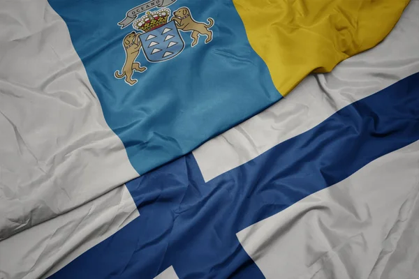 Színes finn zászló lobogtatása és a Kanári-szigetek nemzeti lobogója. — Stock Fotó