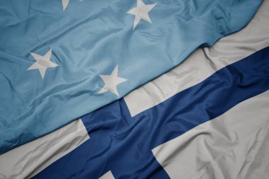 Finlandiya 'nın renkli bayrağını sallıyor ve Mikronezya Birleşik Devletleri bayrağını sallıyor. .