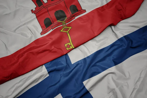 Sventolando bandiera colorata della Finlandia e bandiera nazionale di gibraltar . — Foto Stock