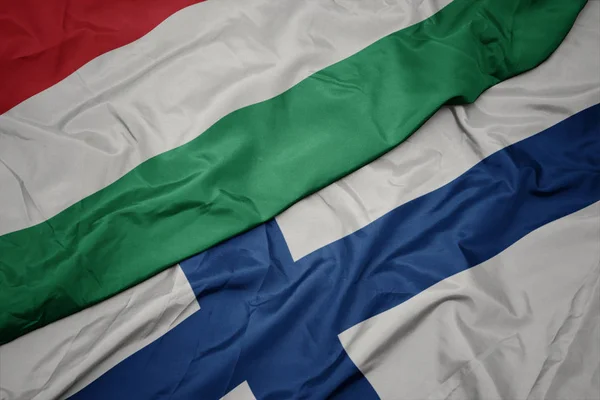 Acenando bandeira colorida de finlândia e bandeira nacional de húngaro . — Fotografia de Stock