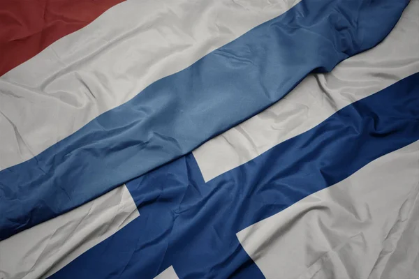 Viftande färgglada flagga Finland och nationell flagga luxembourg. — Stockfoto