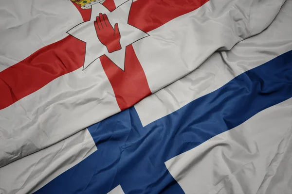 Acenando bandeira colorida da Finlândia e bandeira nacional da Irlanda do Norte . — Fotografia de Stock