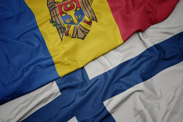 Ondeando colorida bandera de Finlandia y bandera nacional de Moldavia . —  Fotos de Stock