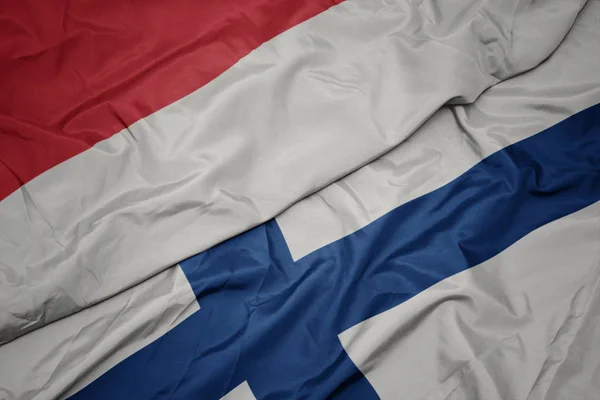 Sventolando bandiera colorata della Finlandia e bandiera nazionale dell'indonesia . — Foto Stock