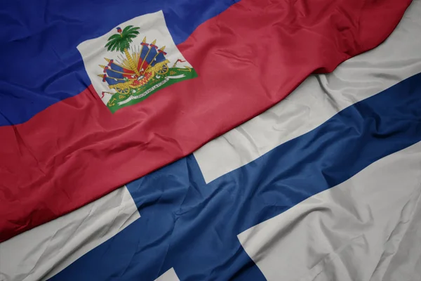 Agitant drapeau coloré de la Finlande et drapeau national de haiti . — Photo