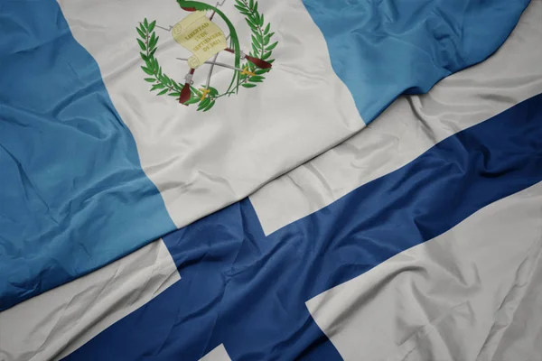 Κυματίζει πολύχρωμη σημαία της Φινλανδίας και εθνική σημαία της guatemala. — Φωτογραφία Αρχείου