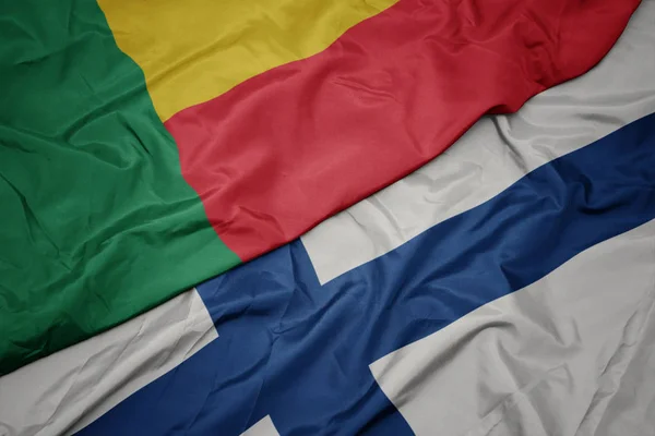 Sventolando bandiera colorata della Finlandia e bandiera nazionale del Benin . — Foto Stock