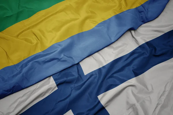 Sventolando bandiera colorata della Finlandia e bandiera nazionale del Gabon . — Foto Stock