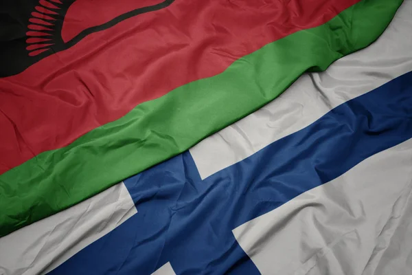 Sventolando bandiera colorata della Finlandia e bandiera nazionale del Malawi . — Foto Stock