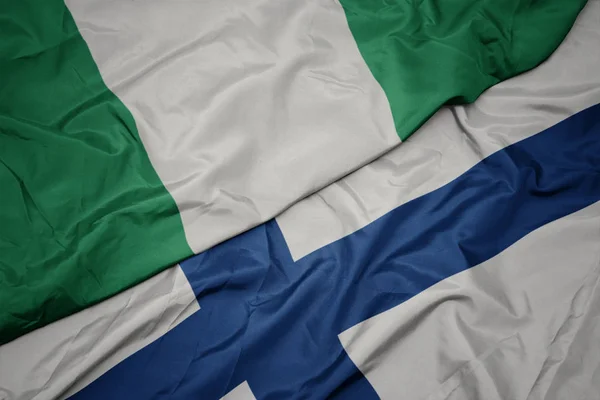 Sventolando bandiera colorata della Finlandia e bandiera nazionale della Nigeria . — Foto Stock