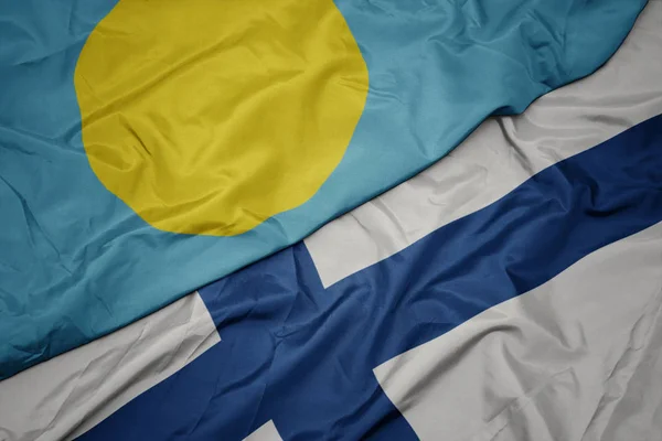 Machająca kolorowa flaga Finlandii i flaga narodowa Palau . — Zdjęcie stockowe