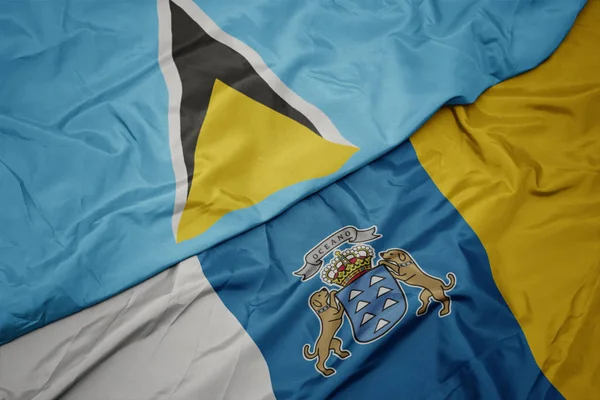 Agitant drapeau coloré des îles Canaries et drapeau national de Sainte-Lucie . — Photo
