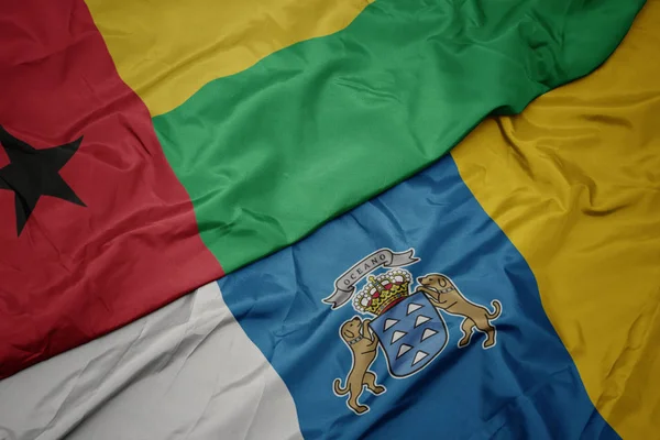 Zwaaiende vlag van Canarische eilanden en nationale vlag van Guinea bissau. — Stockfoto