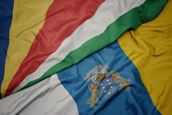Mávání barevnou vlajkou Kanárských ostrovů a národní vlajkou Seychel. — Stock fotografie
