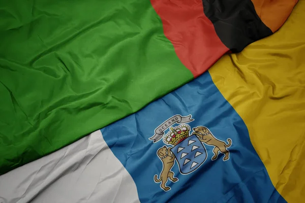 Színes zászló lobogtatása a Kanári-szigeteken és Zambia nemzeti lobogója. — Stock Fotó