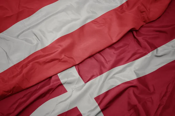 Zwaaiende vlag van Denemarken en nationale vlag van Oostenrijk. — Stockfoto