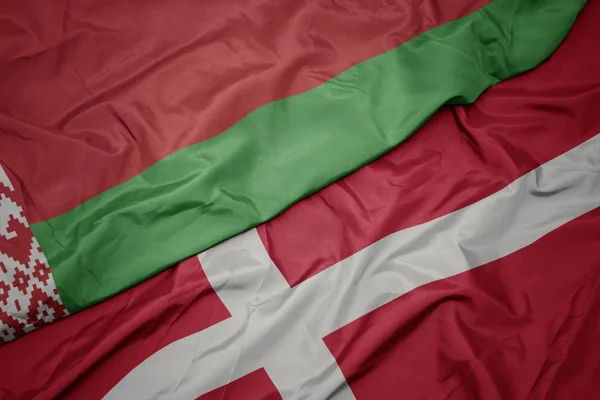 Acenando bandeira colorida de denmark e bandeira nacional de belarus . — Fotografia de Stock