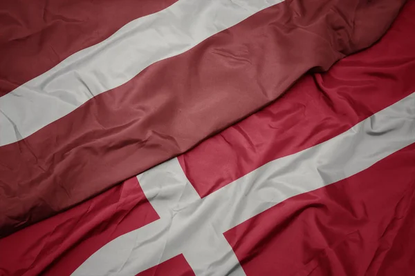 Agitant le drapeau coloré du Danemark et le drapeau national de latvia . — Photo