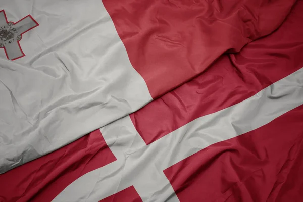 Acenando bandeira colorida de denmark e bandeira nacional de malta . — Fotografia de Stock