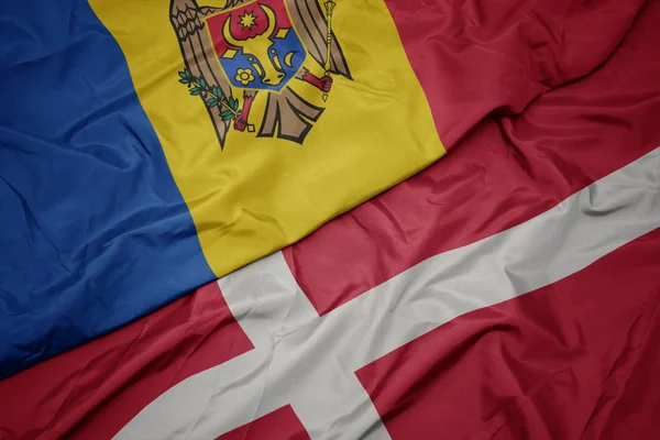 Ondeando colorida bandera de denmark y bandera nacional de moldova . —  Fotos de Stock