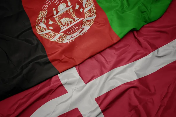 Ondeando colorida bandera de denmark y bandera nacional de afghanistan . — Foto de Stock