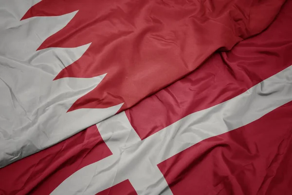 waving colorful flag of denmark and national flag of bahrain.