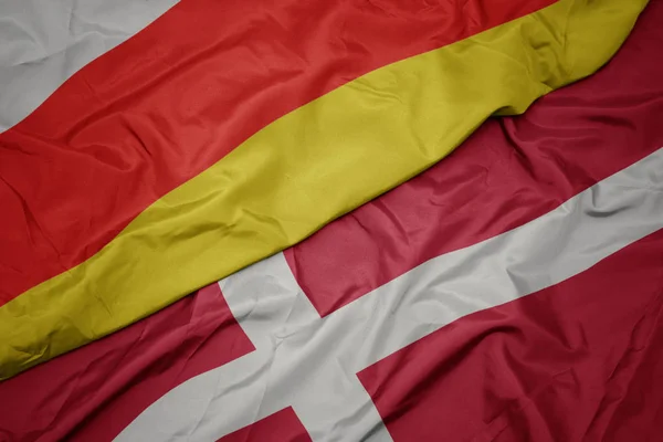 Waving colorful flag of denmark and national flag of south ossetia. — Stock Photo, Image