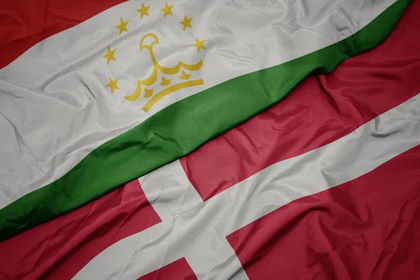 Размахивая красочным флагом денмарка и национального флага Таджикистана . — стоковое фото