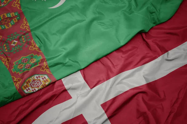 Acenando bandeira colorida de denmark e bandeira nacional do Turquemenistão . — Fotografia de Stock