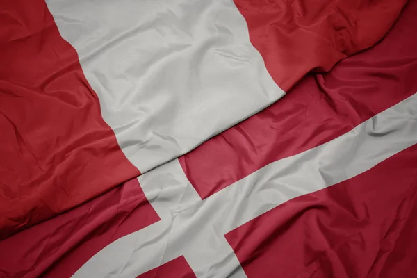 Agitant le drapeau coloré du Danemark et le drapeau national du Pérou . — Photo