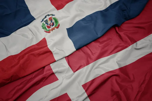 Ondeando colorida bandera de denmark y bandera nacional de República Dominicana . —  Fotos de Stock