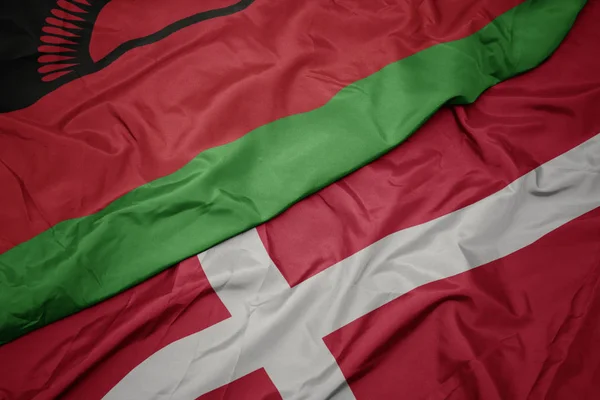 Machanie kolorową flagą denmarku i flagą narodową Malawi. — Zdjęcie stockowe