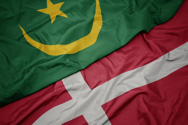 Mávání barevnou vlajkou denmarku a státní mauritánské vlajky. — Stock fotografie