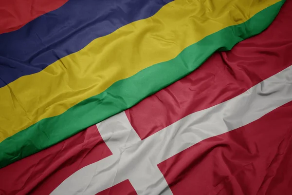 Sventolando bandiera colorata di denmark e bandiera nazionale di mauritius . — Foto Stock