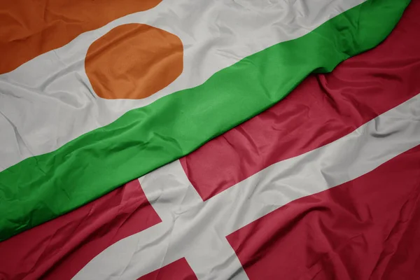 Acenando bandeira colorida de denmark e bandeira nacional de niger . — Fotografia de Stock