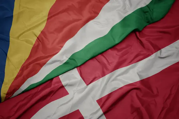 Zwaaiende vlag van Denemarken en nationale vlag van de Seychellen. — Stockfoto