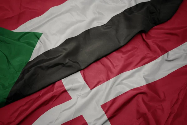 Размахивая красочным флагом денмарка и национальным флагом Судана . — стоковое фото