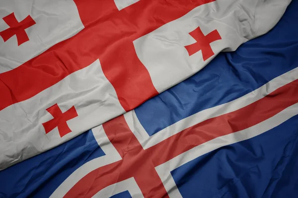 Schwenken bunte Flagge von Island und Nationalflagge von Georgien. — Stockfoto