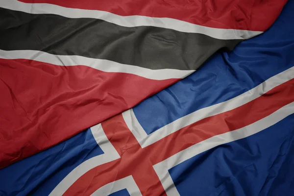 Zwaaiende vlag van IJsland en nationale vlag van trinidad en tabak. — Stockfoto