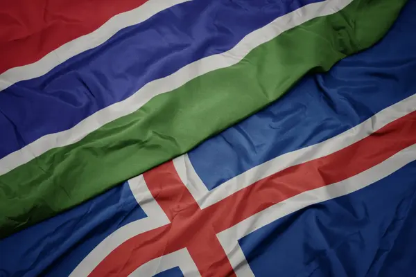 Viftar med färgrik flagg från Island och nationell flagga för gambia. — Stockfoto