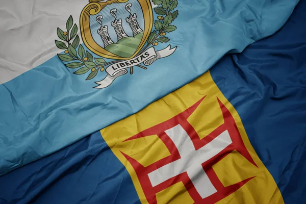 Mává barevnou vlajkou Madeiry a národní vlajkou San Marina. — Stock fotografie