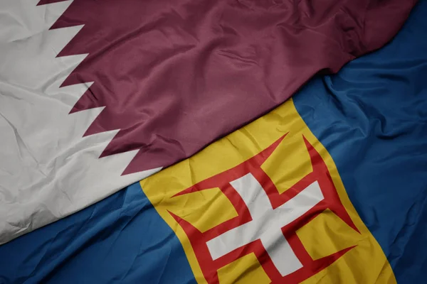 Waving colorful flag of madeira and national flag of qatar. — Stock Photo, Image