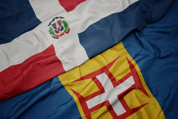 Ondeando colorida bandera de Madeira y bandera nacional de la República Dominicana . —  Fotos de Stock