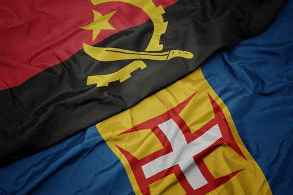 Machanie kolorową flagą Madery i flagą narodową angoli. — Zdjęcie stockowe