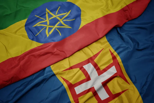 Mávání barevnou vlajkou madeiry a národní vlajky etiopie . — Stock fotografie