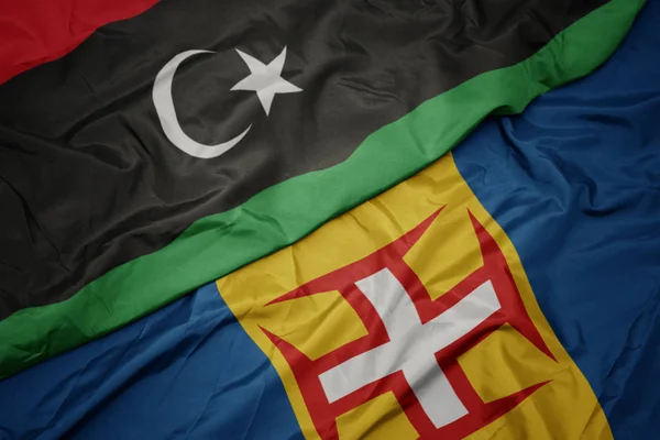 Mávání barevnou vlajkou madeiry a národní libyjské vlajky. — Stock fotografie