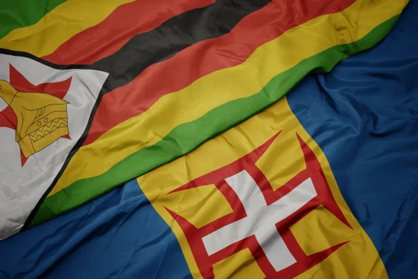 Sventolando bandiera colorata di madeira e bandiera nazionale di zimbabwe . — Foto Stock