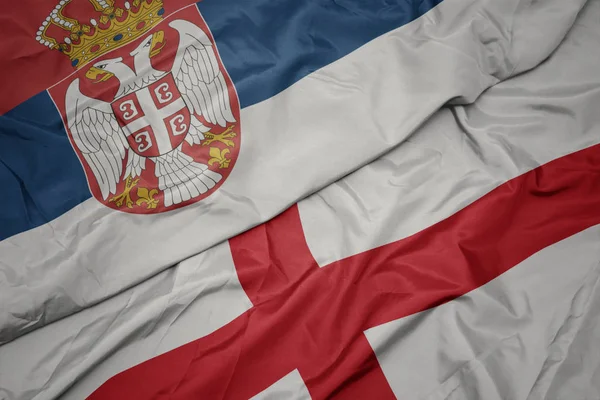 挥动着五彩缤纷的英格兰国旗和塞尔维亚国旗. — 图库照片