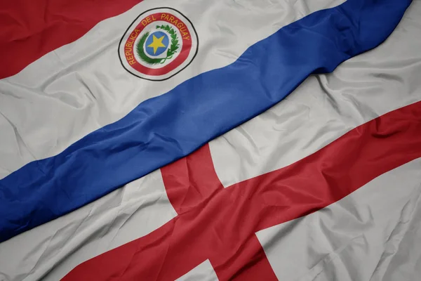 Agitant drapeau coloré de l'Angleterre et drapeau national du paraguay . — Photo